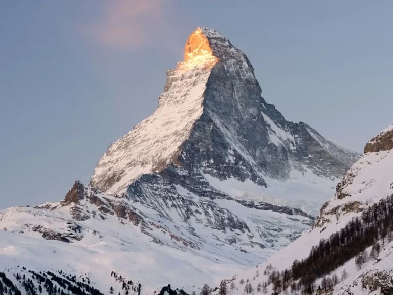 Mountain landscape at dusk with snow-covered peaks.